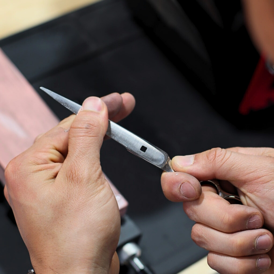 Close-up of hands holding part of a hair shear with a blurred background